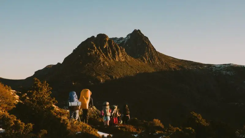 a group of hikers at the cradle mountain hike in tasmania with the mountain in the background