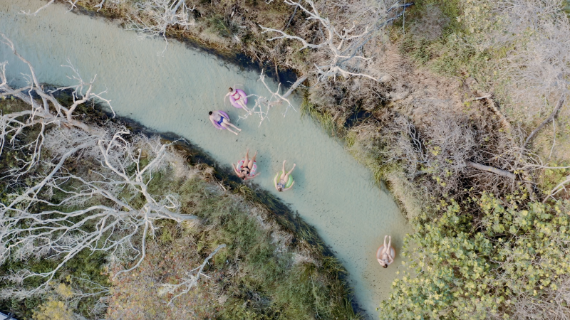 an aerial photo of a group of friends floating down Eli Creek on K'gari