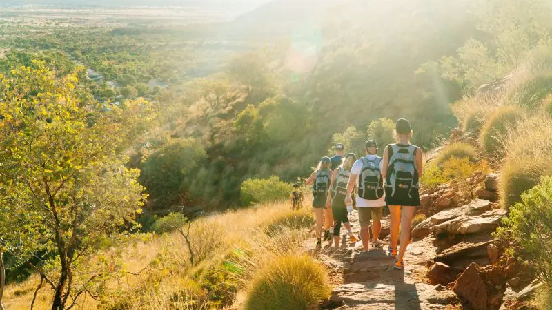 Hikers navigate a scenic, rocky trail on the 3 Day Uluru Rock The Centre Tour departing from Alice Springs in Australia’s Red Centre.