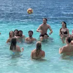 a group of friends having fun with a ball in a lake