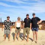 backpackers exploring K'gari at Maheno shipwreck in the background with Peterpans