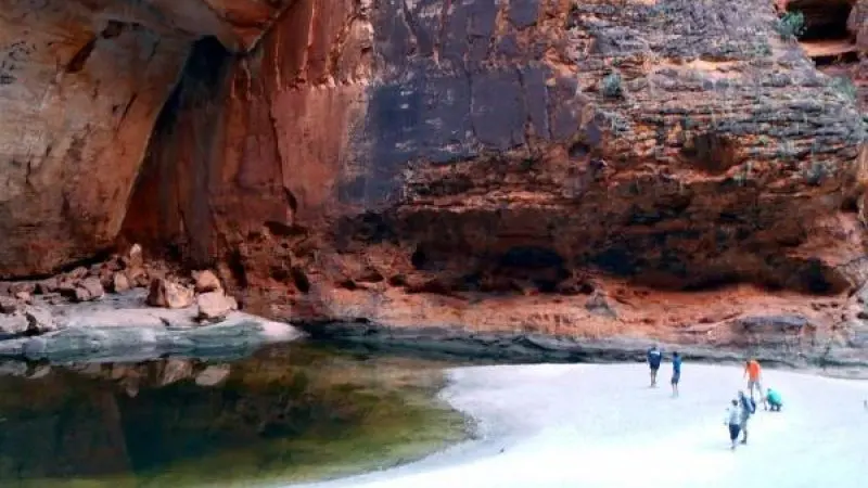Adventurers explore sandy terrain by a scenic rock pool on the 10 Day Broome to Darwin 4WD Kimberley Adventure tour in Australia.