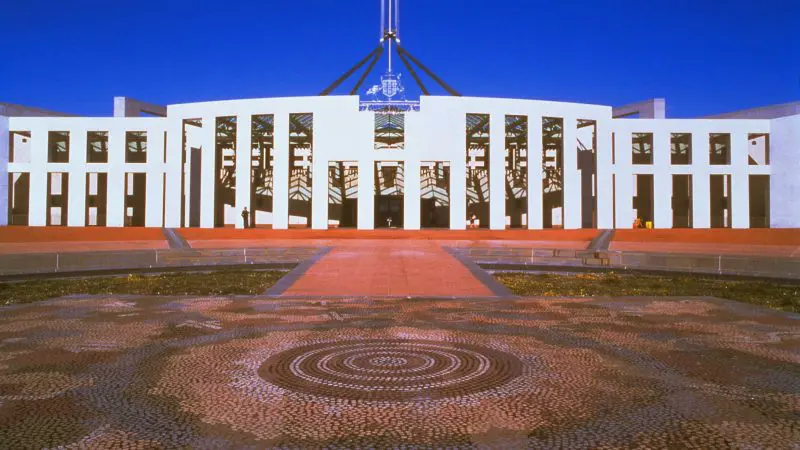 Parliament House Canberra, iconic landmark for day trips from Sydney, under clear blue skies and a striking patterned stone courtyard.