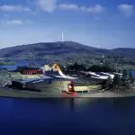 Striking modern building with vibrant roof on lush island, ideal for Canberra day trips from Sydney, surrounded by water and greenery.