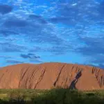 Uluru majestically towers under a vivid blue sky with scattered clouds on the 3 Night Uluru Rock The Centre Alice Springs to Yulara tour.