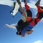 Experience the thrill of tandem skydiving upside down near Sydney with aeroplane overhead, clear blue sky, unforgettable adventure.