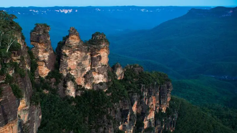 The iconic Three Sisters sandstone peaks tower over lush forest in Australia’s Blue Mountains, a must-see on 1 Day Blue Mountains Tours.