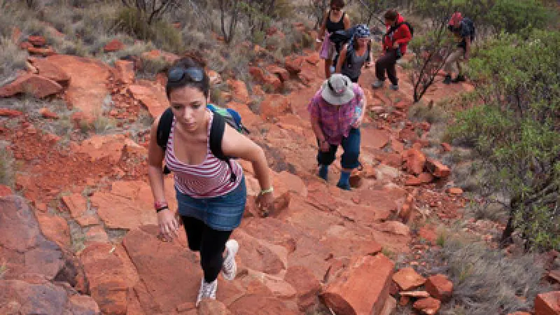 Adventurers trek a rugged, red dirt trail near Yulara on the 3 Night Rock The Centre tour, exploring iconic outback landscapes.