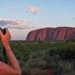 Two women photographing iconic Uluru at sunset on a 3-night adventure tour from Alice Springs to Yulara in Australia’s Red Centre.