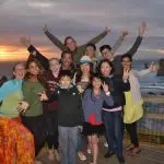 Joyful group with raised arms poses on a scenic boardwalk at sunset during Go West Tours’ 1 Day Great Ocean Road Sunset Tour.