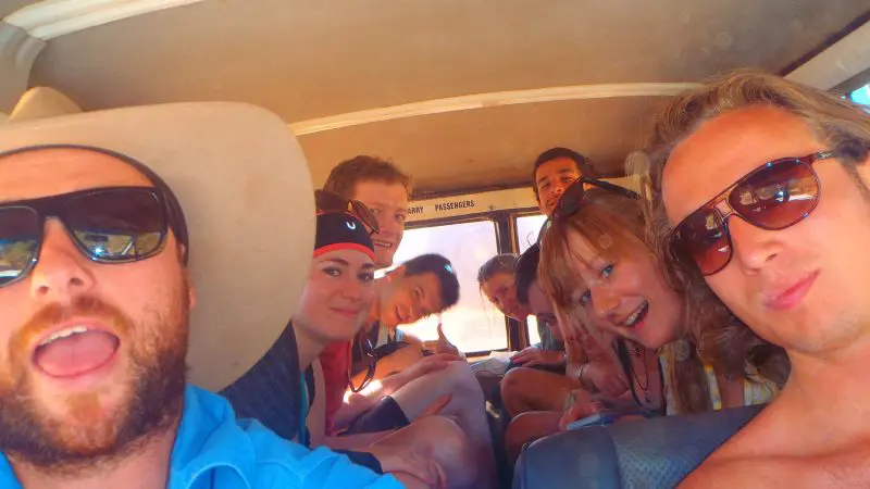 Happy friends enjoy an adventurous Kakadu Tour, sitting close together in a van and capturing a joyful group selfie on their journey.