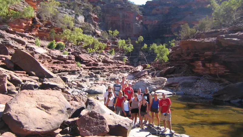 a group of people on red rocks beside a river in Kalbarri