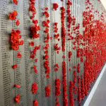 Striking red poppies on a Canberra memorial wall honour fallen soldiers—top spot for your Canberra day trip from Sydney.