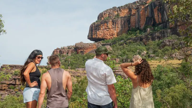 Group of four people explore dramatic rocky cliffs and lush greenery during a guided 4 Day Kakadu Katherine and Litchfield Adventure tour.