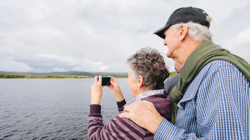 Two pensioners by a serene lake enjoy their Half-Day Noosa Everglades Serenity Cruise with Eco Safaris, capturing unforgettable moments.