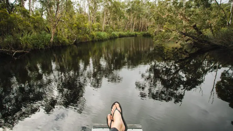 Experience ultimate relaxation along the tranquil Noosa Everglades river on a Half-Day Serenity Cruise with Everglades Eco Safaris; feet in sandals showing.