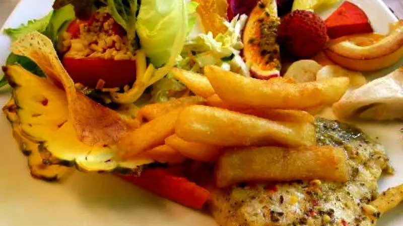 Savour grilled fish, crispy chips, and fresh fruit on a plate—ideal meal after your Daintree Cape Tribulation day tour.