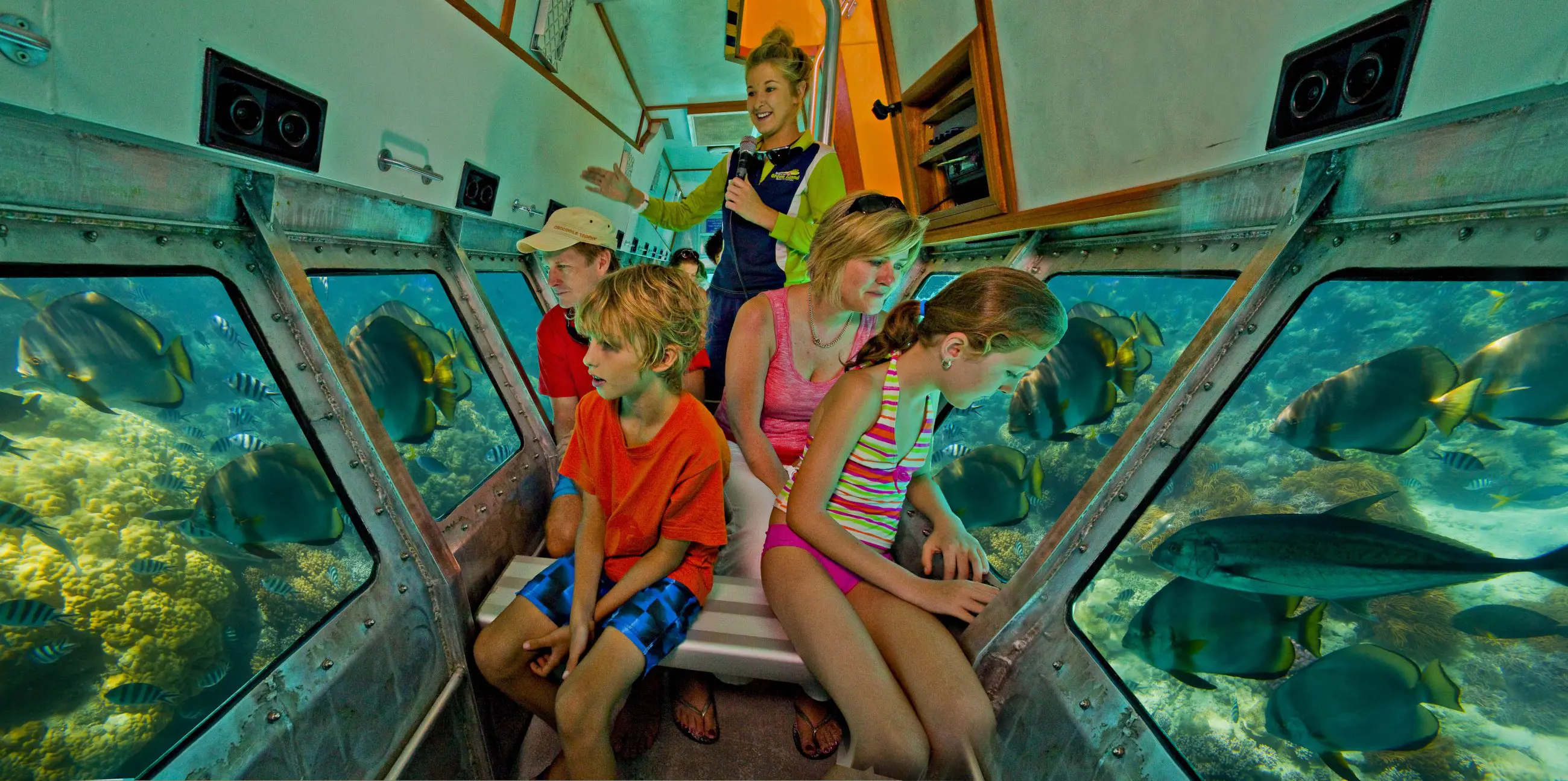 Family explores vibrant marine life and colourful coral reefs from a semi-submarine on a Half Day Green Island tour in crystal waters.