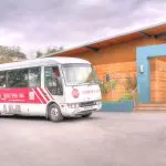 Yarra Valley Wine Experience coach outside a contemporary wooden winery, inviting visitors under overcast skies for premium wine tours.