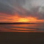 Stunning fiery orange sunset over tranquil ocean waters, ideal for dolphin kayaking on the iconic Great Beach Drive at Rainbow Beach.