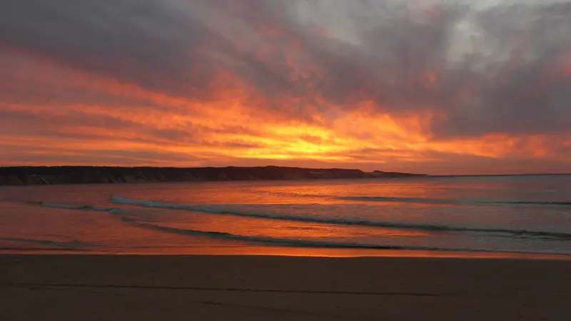 Stunning fiery orange sunset over tranquil ocean waters, ideal for dolphin kayaking on the iconic Great Beach Drive at Rainbow Beach.