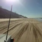 Experience Australia’s longest surfable wave from a vehicle on Beach Drive, with sandy shores, tyre tracks, and scenic dunes.