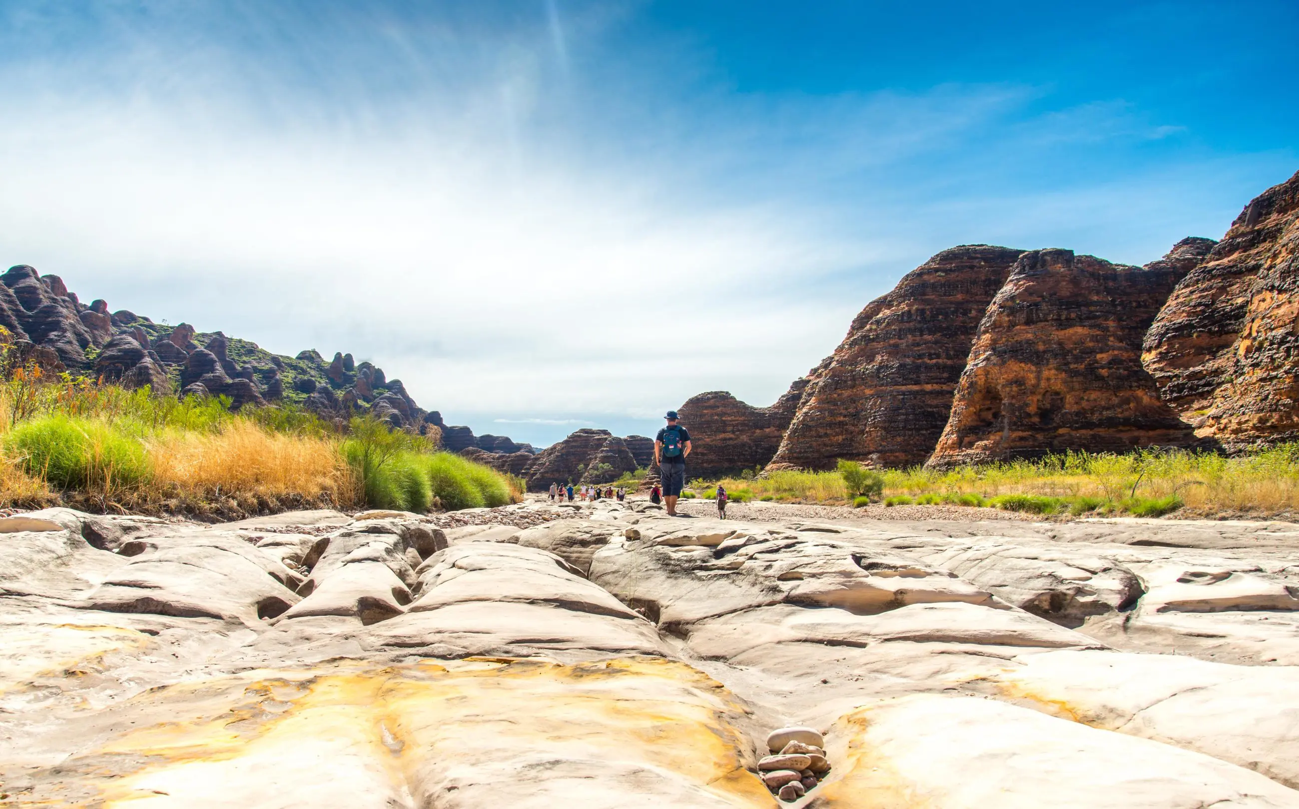 Traveller trekking across a rugged, sunlit riverbed on the 10 Day Broome to Darwin Kimberley Off Road Adventure Tours experience.