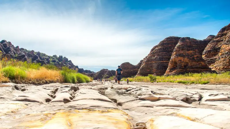 Traveller trekking across a rugged, sunlit riverbed on the 10 Day Broome to Darwin Kimberley Off Road Adventure Tours experience.