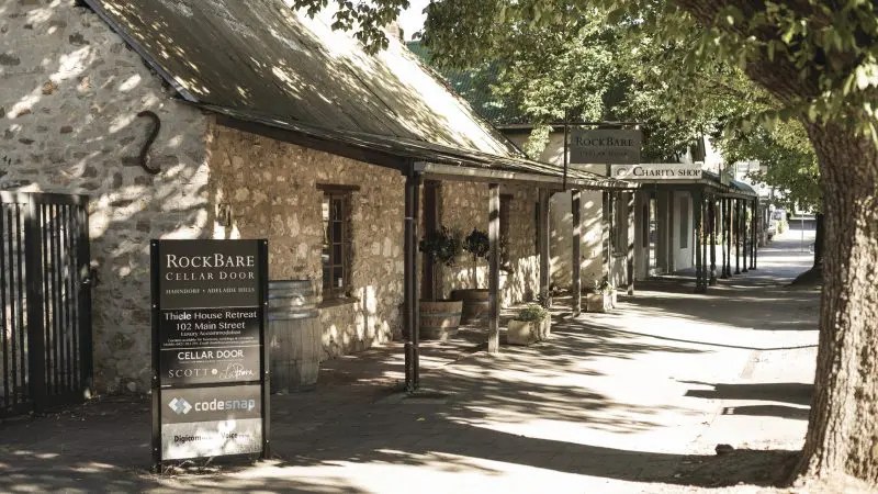 Sun-drenched stone RockBare Cellar Door with clear signage, seen on Hahndorf Adelaide Hills Hop On Hop Off Wine Tour experience.