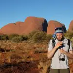 A traveller with a camera explores the desert landscape on the 3 Night Rock The Centre Yulara To Yulara adventure tour in Australia.