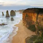 Majestic limestone stacks stand along a golden sandy beach on the Great Ocean Road’s 1 Day 12 Apostles Tour with Go West Tours.