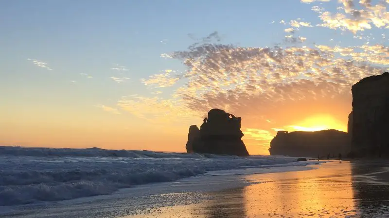 Breathtaking sunset over the ocean on a 1 Day Great Ocean Road Tour by Go West Tours—golden waves shimmer on sandy Australian shores.