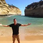 Man with arms wide open on sandy beach enjoying sunset during Go West Tours’ 1 Day Great Ocean Road Sunset Tour, stunning scenery.