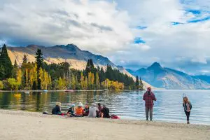 Image of people sitting and standing admiring the view over Queenstown Waterfront with mountains in the Background
