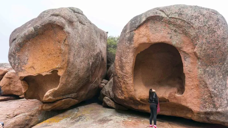 Traveller admires unique hollowed-out boulders on the scenic Wineglass Bay Full Day Tour via Richmond, surrounded by rock formations.