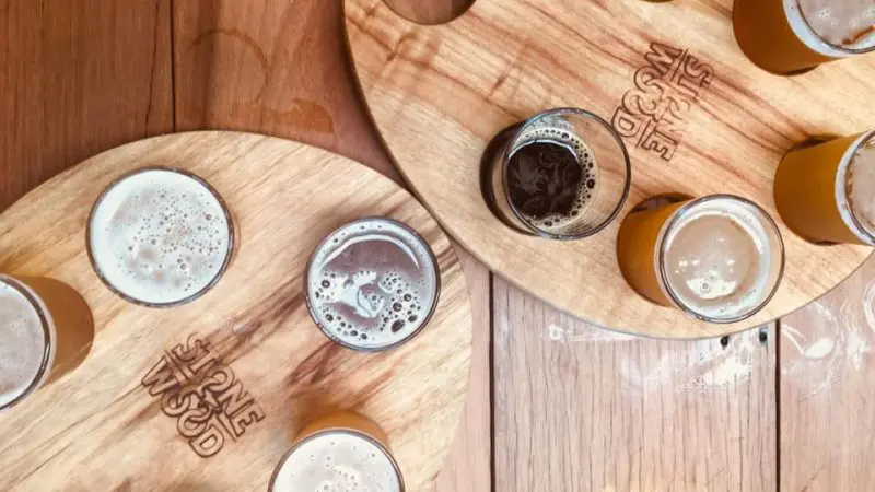 Craft beer tasting experience featuring wooden paddles with assorted glasses, ideal for a full day brewery and distillery tour.