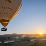 Experience a breathtaking sunrise hot air balloon flight over Melbourne with Global Ballooning Australia, soaring above misty valleys.