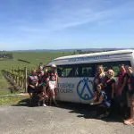Women smiling by a branded Teepee Tours van during a relaxed Yarra Valley Winery Tour in sunlit vineyards, perfect for group outings.