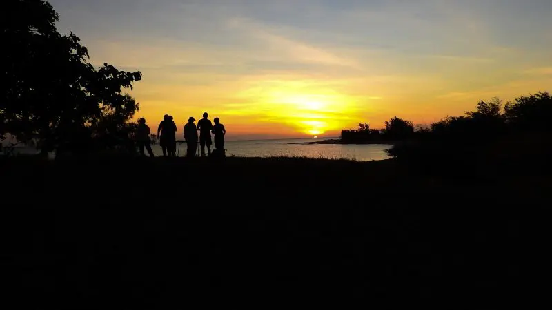 Silhouettes of people by a tranquil lake at sunset, evoking authentic Kakadu Arnhem Land Tour scenery and Australian outback atmosphere.
