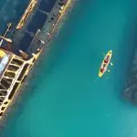 Aerial view of a yellow kayak with two people touring the stunning Moreton Island Wrecks in crystal-clear blue water Adventure.