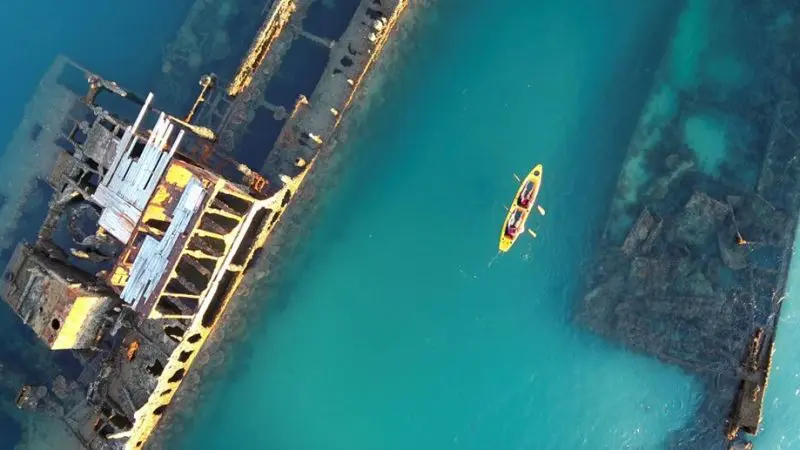 Aerial view of a yellow kayak with two people touring the stunning Moreton Island Wrecks in crystal-clear blue water Adventure.