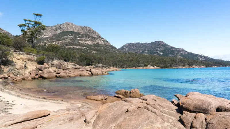 Experience Wineglass Bay’s stunning rocky shoreline, crystal-clear blue water, pristine sandy beach, and lush forested mountains.