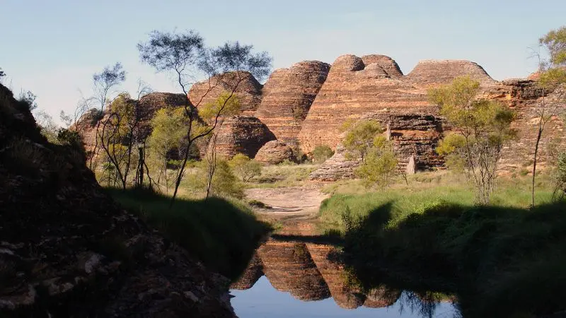 Iconic, beehive-shaped rock formations mirrored in a tranquil stream, featured on Darwin to Perth Adventure with Broome Accommodation.