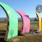 Vibrant abstract outdoor sculptures resembling curved fins, displayed along the scenic 1 Day Lake Mountain Snow Waterfalls Tour route.
