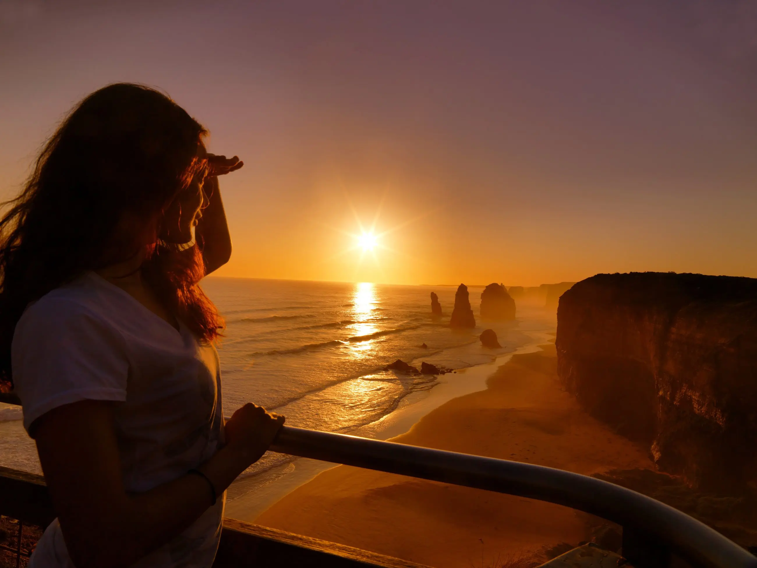 Traveller experiences the iconic Great Ocean Road Sunset Tour, viewing the sun set over dramatic coastal cliffs and breathtaking seascapes.