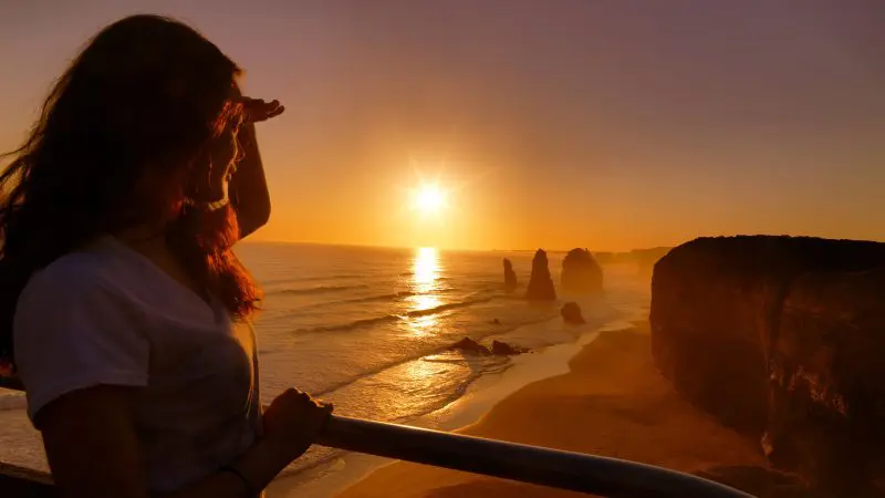 Traveller experiences the iconic Great Ocean Road Sunset Tour, viewing the sun set over dramatic coastal cliffs and breathtaking seascapes.