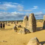 Travellers discover towering limestone pillars amid golden desert sands on the 10 Day Broome to Perth West Coast Adventure tour.