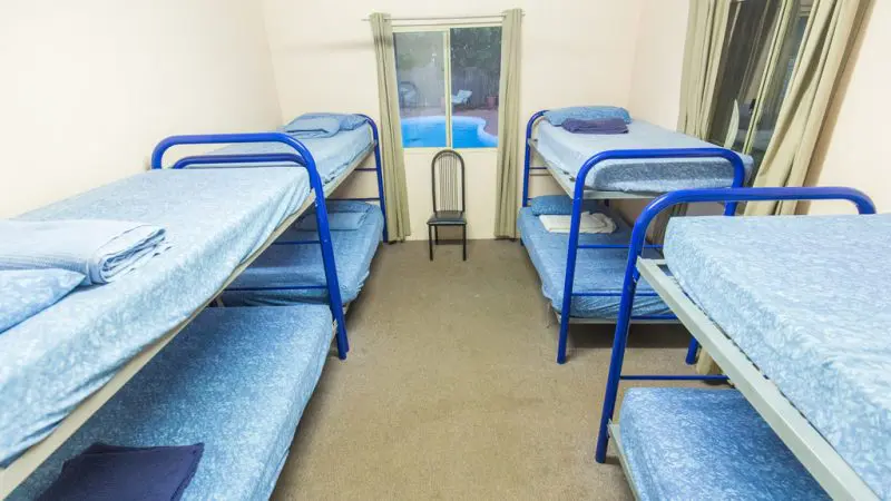 Spacious room with six blue bunk beds and fresh towels, ideal for Perth to Darwin adventure tours and Broome accommodation packages.