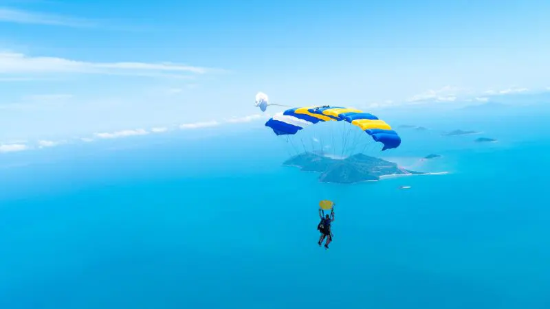 Thrilling paraglider soaring above the expansive blue ocean, evoking a Wollongong 15,000ft tandem skydive adventure experience.