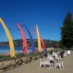 Vibrant flags flutter near a picturesque beachside lounge, ideal for Celebtime Tours' top-rated 1 Day Home Away getaway experience.
